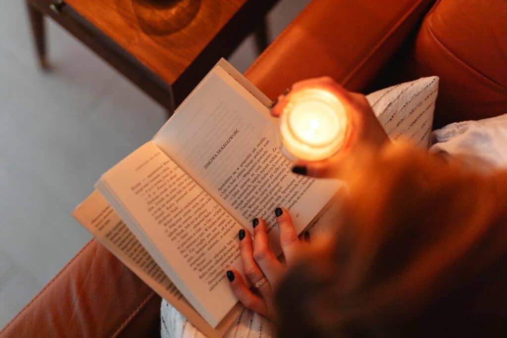 woman reading a book by candle light